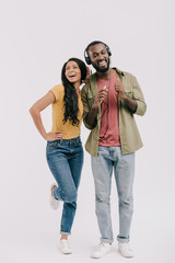 smiling african american girlfriend eavesdropping boyfriend music isolated on white