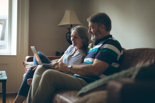 Senior couple using laptop in living room