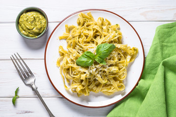 Tagliatelle pasta with pesto sauce and parmesan on white.