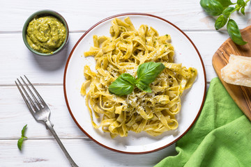 Tagliatelle pasta with pesto sauce and parmesan on white.