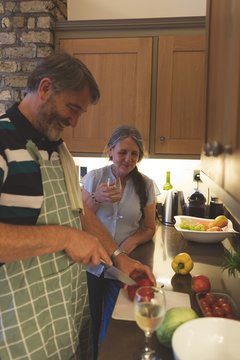 Senior couple cutting vegetable in kitchen