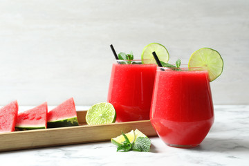 Summer watermelon drink in glasses and sliced fruits on table