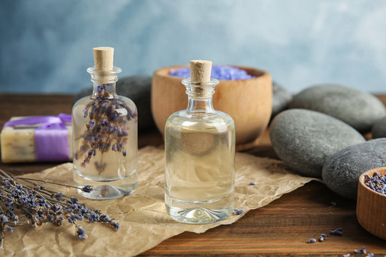 Bottles with natural herbal oil and lavender flowers on table against blurred background