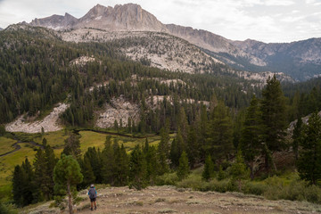 Female backpacker looks at granite valleys at sunset in California's Sierra Nevada along the John Muir Trail