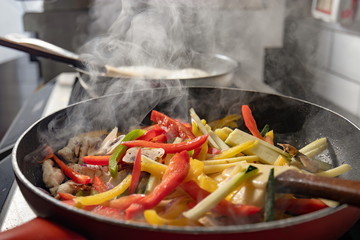Vegetables and chicken prepared in red frying pan