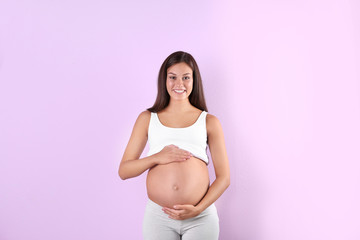 Happy pregnant woman posing on color background