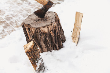 ax sticks out in stump against background of white snow