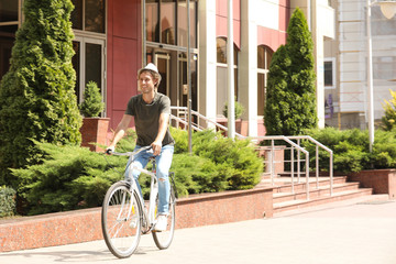 Fototapeta na wymiar Handsome young man riding bicycle on city street