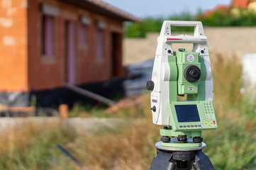 Surveyor measuring equipment (theodolit) on construction site with house in background