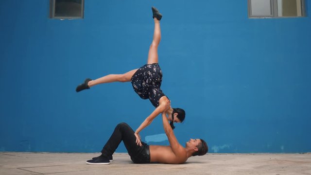 Dance partners demonstrating sensual dance pattern with acrobatics in slow motion on blue background. Dancing outdoors in the city