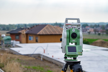 Surveyor measuring equipment (theodolit) on construction site with house in background
