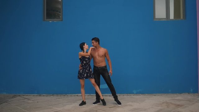 Dance partners demonstrating sensual dance pattern with acrobatics in slow motion on blue background. Dancing outdoors in the city