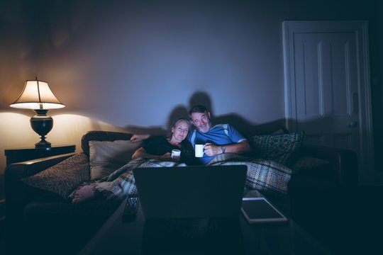 Senior couple watching laptop while having coffee at home