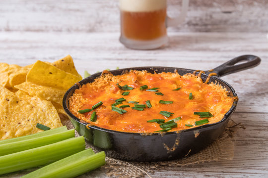 Baked cheese dip with chips, celery and beer