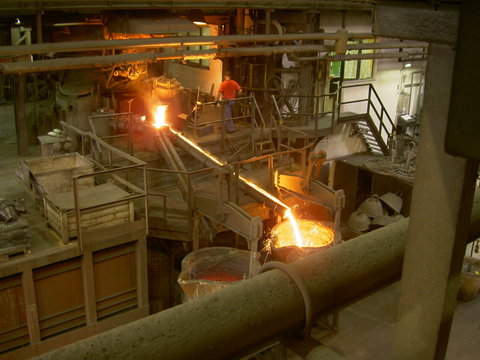 Metal flowing to conteiner in foundry, image