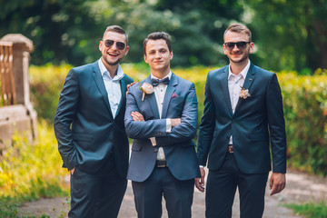 Groomsmen and groom posing outdoors on the wedding day. Funny wedding moment for best groom friends. Mens hug each other.