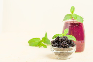 Blackberry smoothie - organic raw drink with fresh ripe forest berries on pastel yellow background.