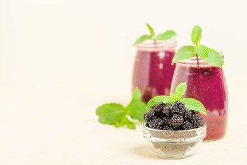 Blackberry smoothie - organic raw drink with fresh ripe forest berries on pastel yellow background.
