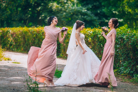 Bride And Bridesmaid In Nature With Bouquets Of Flowers. Funny Wedding Moments, Bride Show Bridesmaids Her New Ring. Girls In Shock.