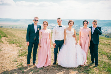 Bride and groom with happy groomsmen and bridesmaids having fun and popping champagne, newlyweds...
