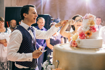 A bride and a groom is cutting their wedding cake. Newltweds couple blurred behind wedding cake.