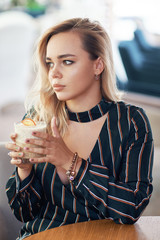 Beautiful woman holding a cocktail in her hands while sitting at