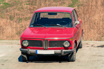 Fototapeta na wymiar Old retro polish car in red standing in parking lot by field