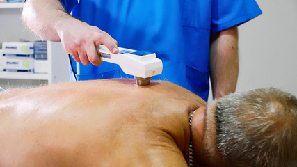 Senior male patient receive electrostatic therapy procedure on his back.