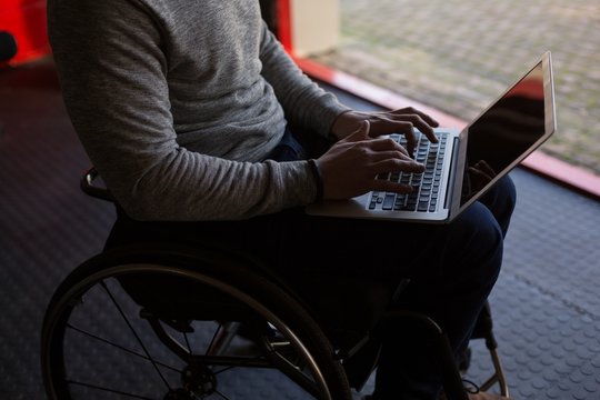Disabled man using laptop in workshop