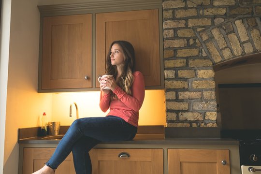 Woman having coffee in kitchen at home