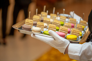 The waiter serves an expensive dessert of macaroons. Macaroon in the restaurant