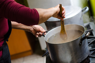 Hand of a woman adding ingredients to the pot where the food is cooking