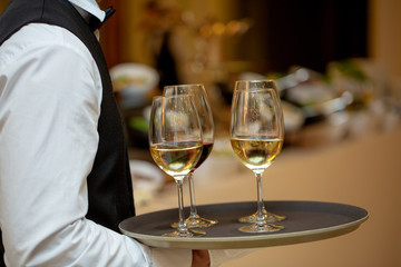 Glasses with wine on a tray. Meeting with guests. The waiter carries a tray with wine