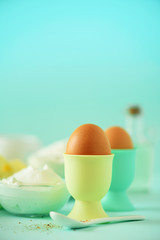 Bakery food frame, cooking concept. Different baking ingredients - butter, sugar, flour, milk, eggs, oil, spoon, rolling pin, brush, whisk over blue background. Copy space
