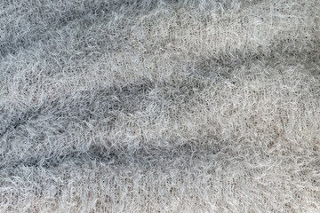 Background of soft, fluffy knit fabric. Gray knitted texture.