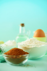 Bakery food frame, cooking concept. Different baking ingredients - butter, sugar, flour, milk, eggs, oil, spoon, rolling pin, brush, whisk over blue background. Copy space