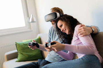 Happy young couple playing video games with virtual reality headsets