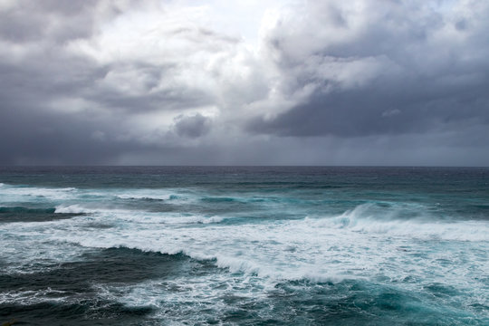 Fototapeta Dark storm clouds above rough waves in ominous seascape in the open ocean