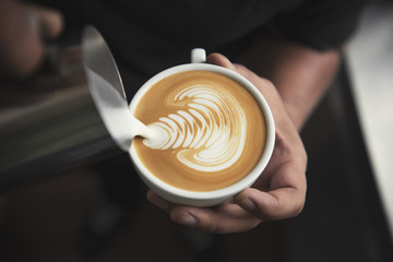 Barista making latte or Cappuccino art with frothy foam, coffee cup in cafe.