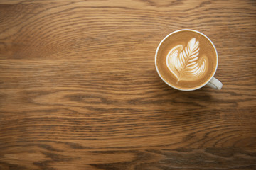 latte or Cappuccino with frothy foam, coffee cup top view on wood table in cafe.