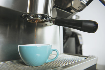 Barista using coffeemaker extraction for espresso shot in cafe.