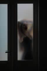 Silhouette of woman hidden behind glass door, mystery concept. Mystery woman with blur filter
