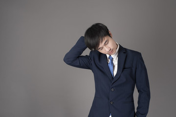 Business man is having neck pain ,grey background in studio