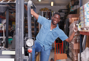 Glad worker on forklift in building store