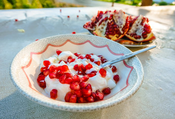 Healthy pomegranate and yogurt breakfast on a table outdoors - Powered by Adobe