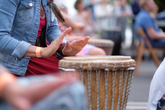 The hands of a woman playing on an African djembe drum, at a percussion music festival