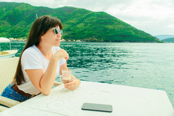 woman sitting in cafe on perast seaside in montenegro eating ice cream