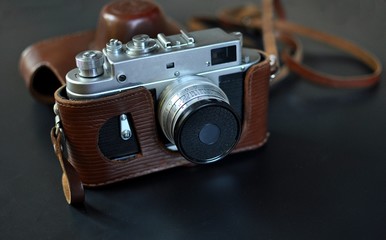 Fototapeta na wymiar Vintage old film camera with brown leather case, on black background