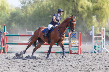 Young woman riding horse on her course in show jumping equestrian competition