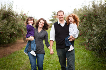 Fototapeta premium Happy Family Walking in Apple Orchard in Autumn